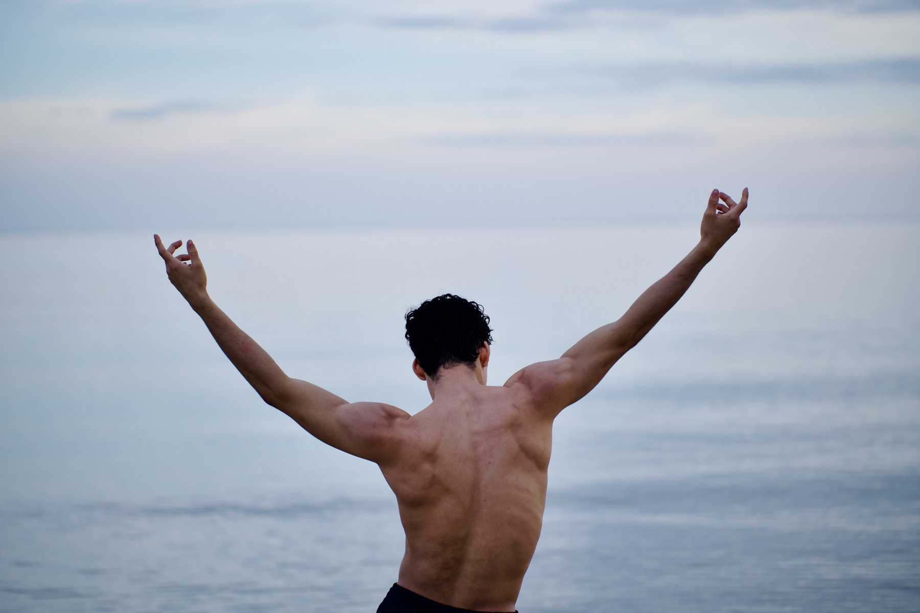 João extending his arms toward the ocean
